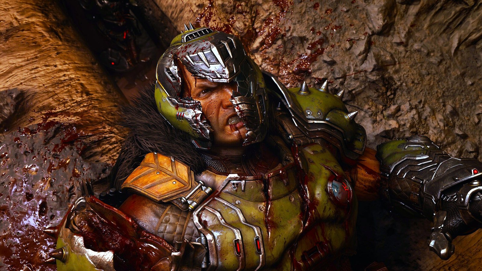 A warrior wearing a battle-scarred helmet and green armor lies covered in blood on a gravelly surface. His facial expression is defiant, with a futuristic and intense atmosphere.