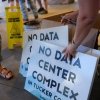 One town renamed its festival “AI Love Irondale Day.” Then came the comments: NPR 16 Volunteers hand out signs protesting a data center complex in West Virginia in June.