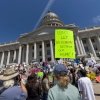 One town renamed its festival “AI Love Irondale Day.” Then came the comments: NPR 18 Demonstrators hold signs in front of the Utah State Capitol to protest the construction of the Stratos data center on May 23, 2026 in Salt Lake City, Utah. The most noticeable sign in the photo reads: