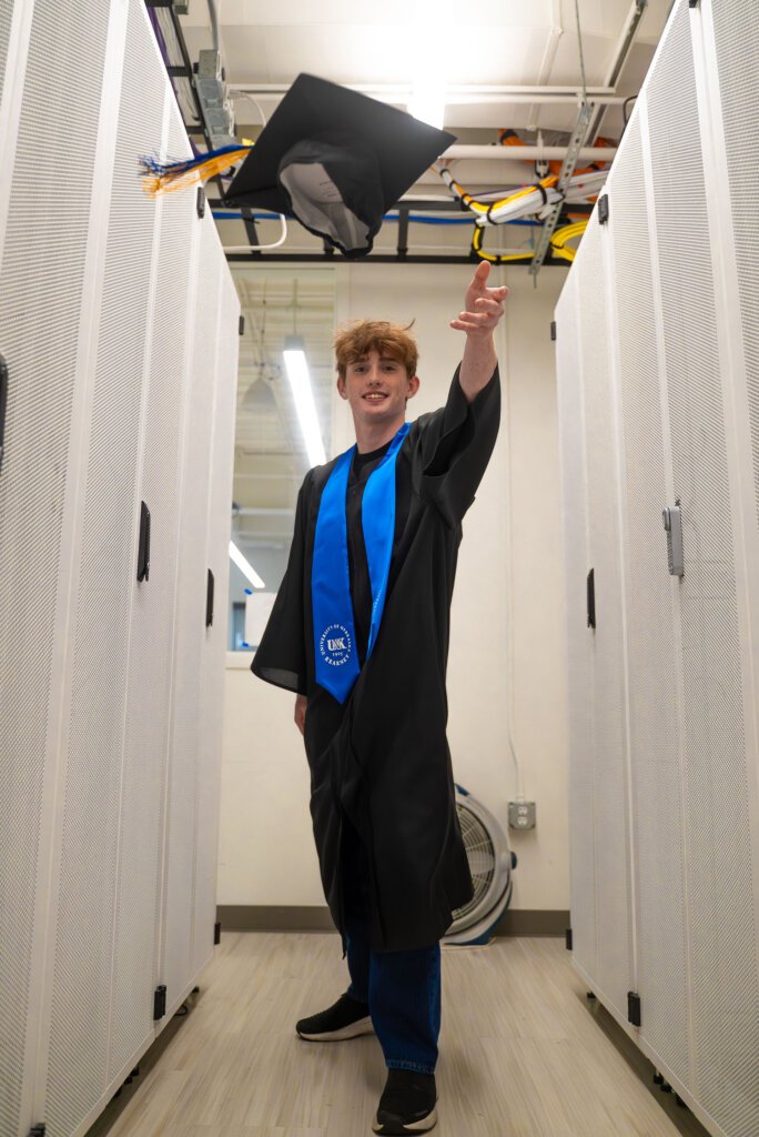 Thomas Safago throws his graduation cap in the air.