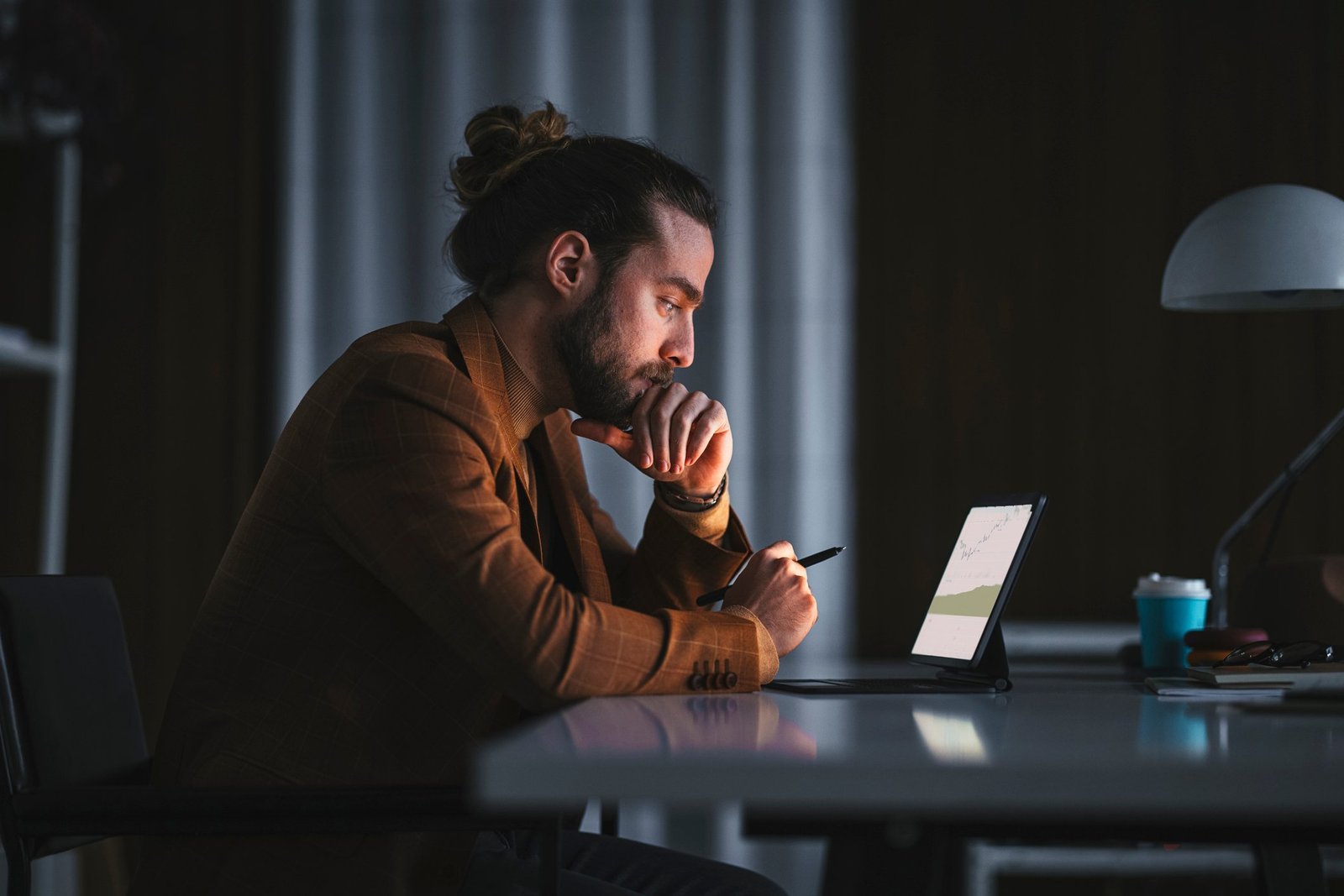 Thoughtful person looking at charts on a tablet computer.