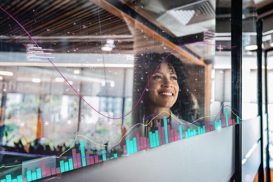 Businesswoman looking at data visualizations on a glass wall in a modern office
