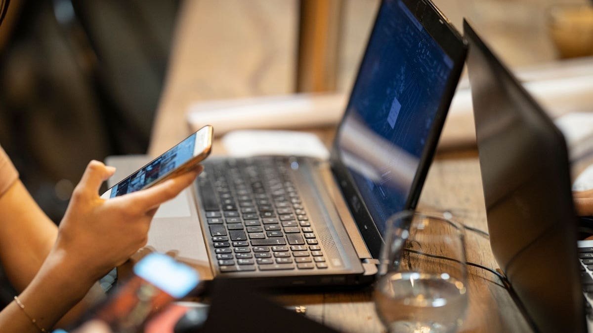 Person holding phone over computer