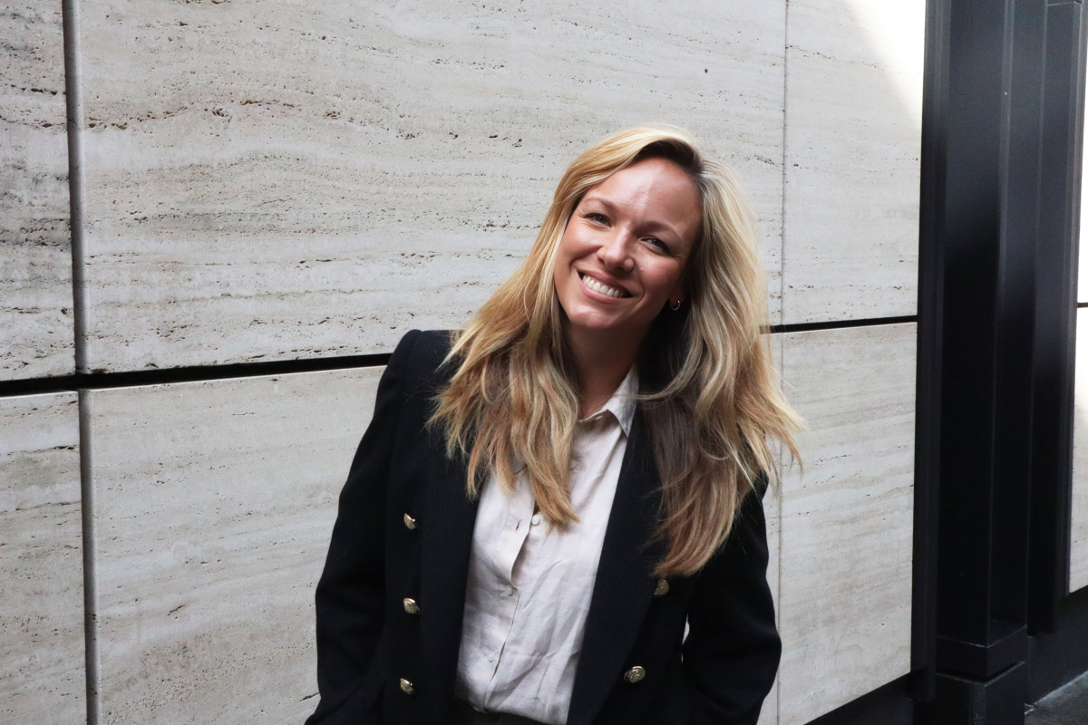 A woman in a black coat smiles.