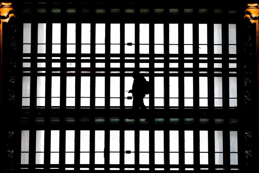 In this file photo, a man walks with a smartphone through the arched windows of Grand Central Terminal in New York City on March 24, 2025.