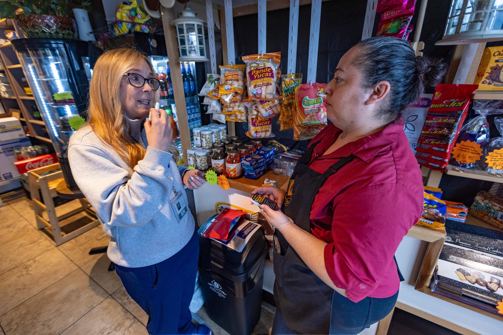 Registered nurse Denise Hartley, co-founder of Atlantic Hill Nursing and Wellness, shows cafe owner Diana Cardona how to administer naloxone. (Jesse Costa/WBUR)