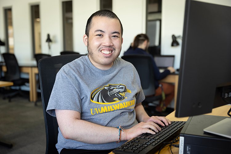 A man sits at a desktop computer with his hands on the keyboard.