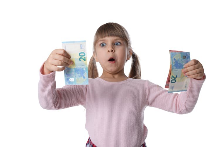Child holds money in hand and looks surprised.