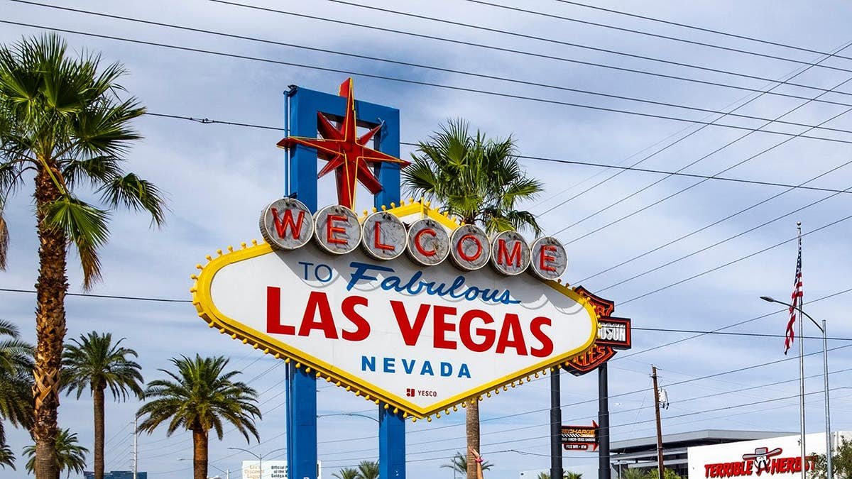 Visitors stand in line in front of the “Welcome to Las Vegas” sign.